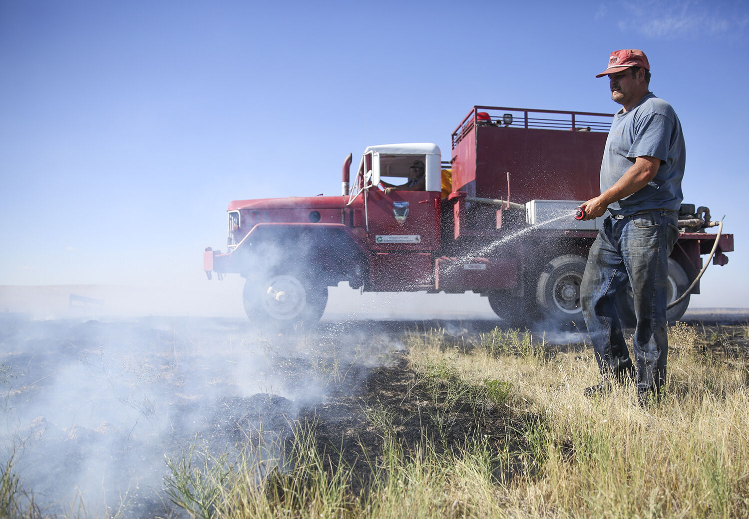 Chase Gosney sprays water on a small fire line